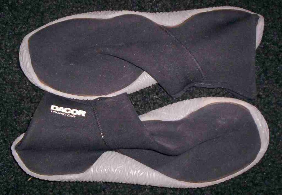 Pair of black DACOR TROPIC CUT diving boots with grey soles on a dark carpet