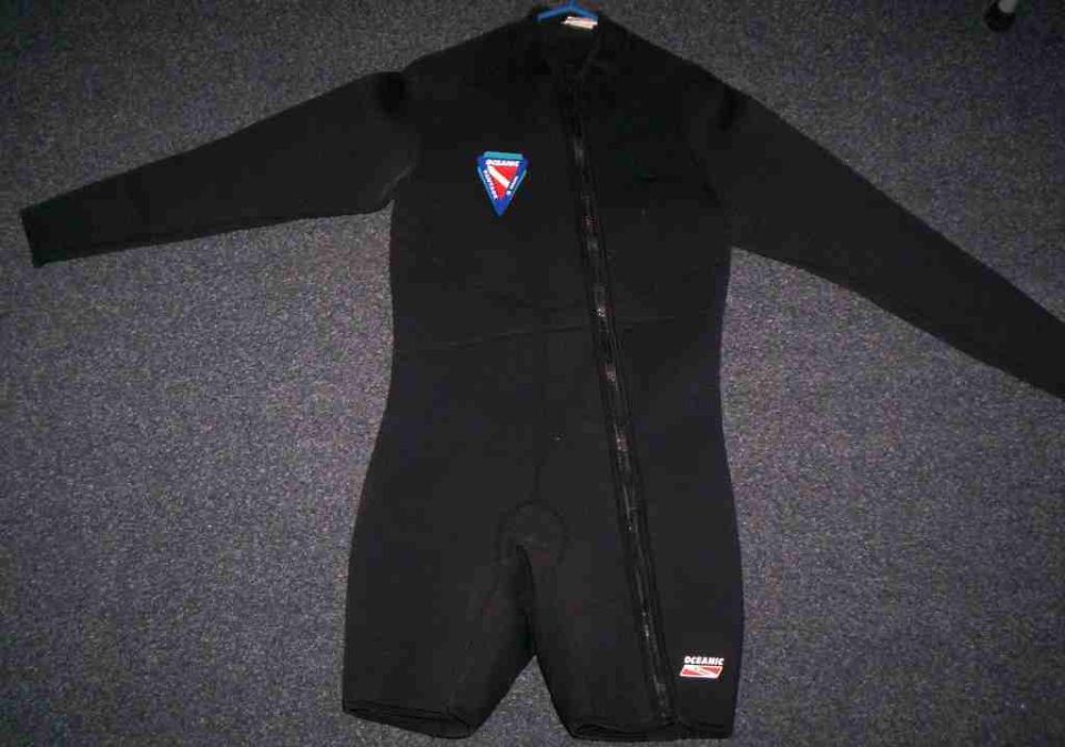 black wetsuit with blue and red dive flag logo on chest, zipper down front, and oceanic logo on leg