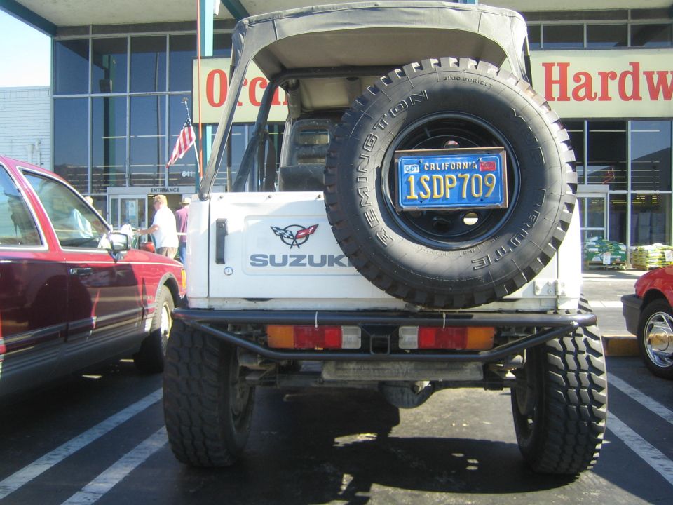 Rear of white Suzuki Samurai with spare Remington mud tire and tube bumper in parking lot