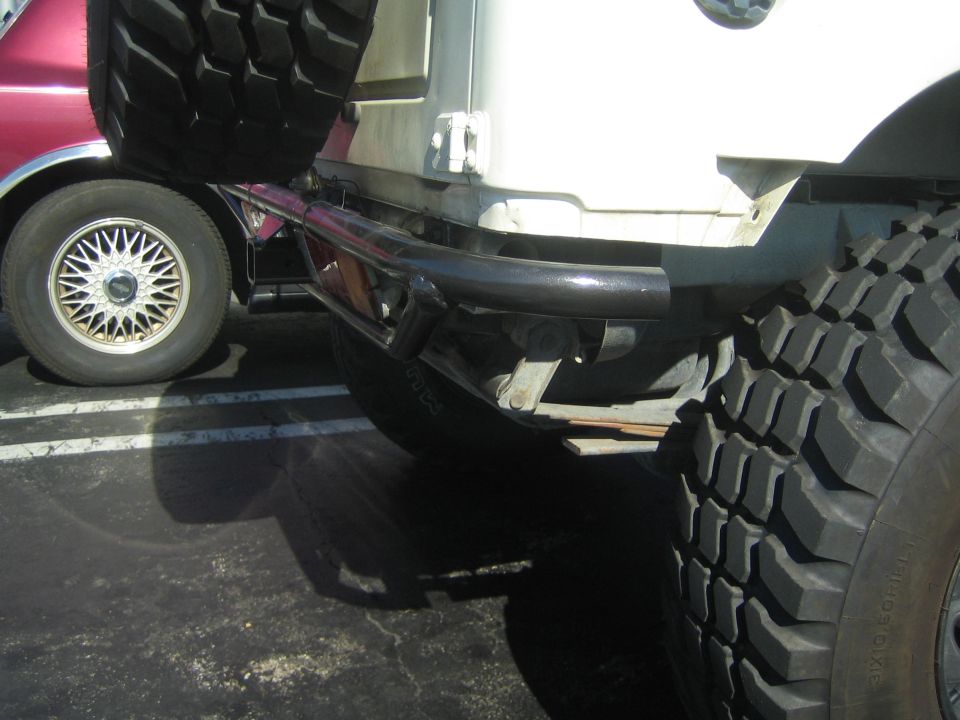 Black tubular bumper on light-colored vehicle with off-road tire in parking lot