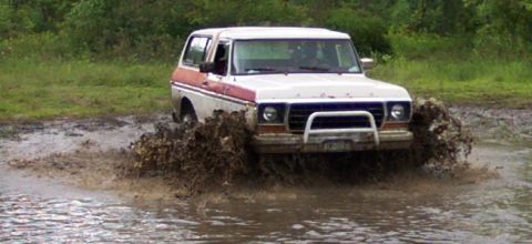 1979 Ford Bronco - This Ford Bronco navigates a muddy terrain, kicking up water and dirt.
