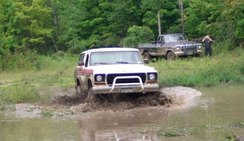 1979 Ford Bronco - Two 4x4 vehicles, a Bronco and an F-Series truck, navigate a muddy off-road course.