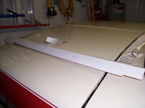 1978 Ford Bronco - A long, thin trim piece lies on the hood of a vehicle, with a small piece of paper nearby.