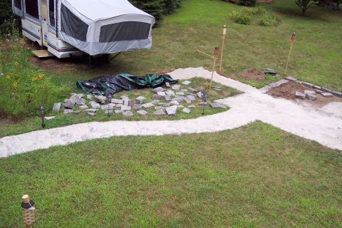 2001 Ford Crown Victoria - Backyard scene shows a pop-up camper and ongoing patio construction with scattered stones and pathway.