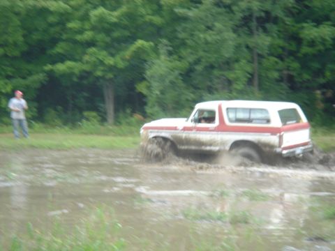 1979 Ford F-250 - Ford Bronco navigating a muddy field with trees in the background.