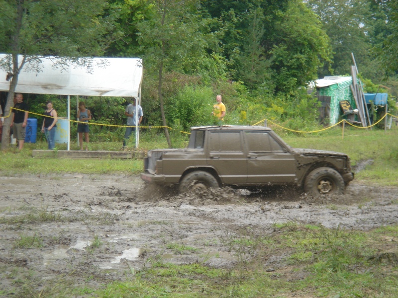 Brown pickup truck with a cap driving through mud, side view