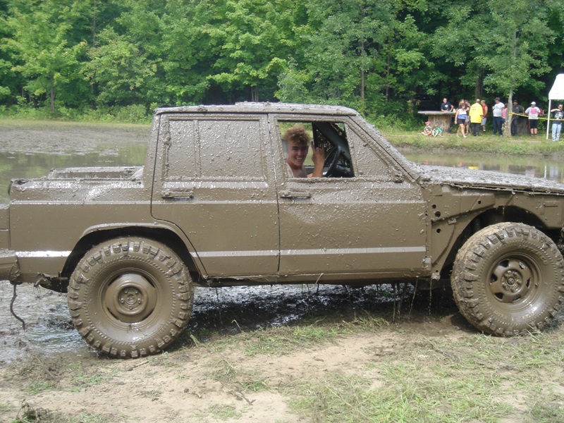 Mud-covered Jeep Comanche pickup truck side view with person inside