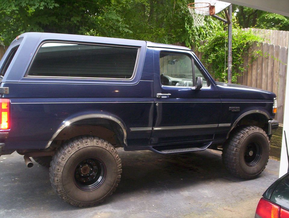 Dark blue Ford Bronco with aftermarket rims and tires, seen from the side