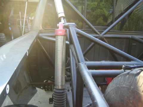 1968 Ford Mustang - The heavy-duty suspension system of an off-road racing truck is visible, a large shock absorber and extensive roll cage.