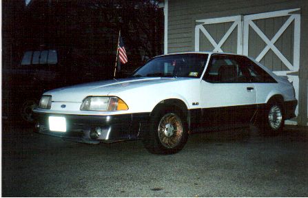 1989 Ford Mustang - This 1989 Ford Mustang GT coupe is shown in a three-quarter front view, parked outside a garage.