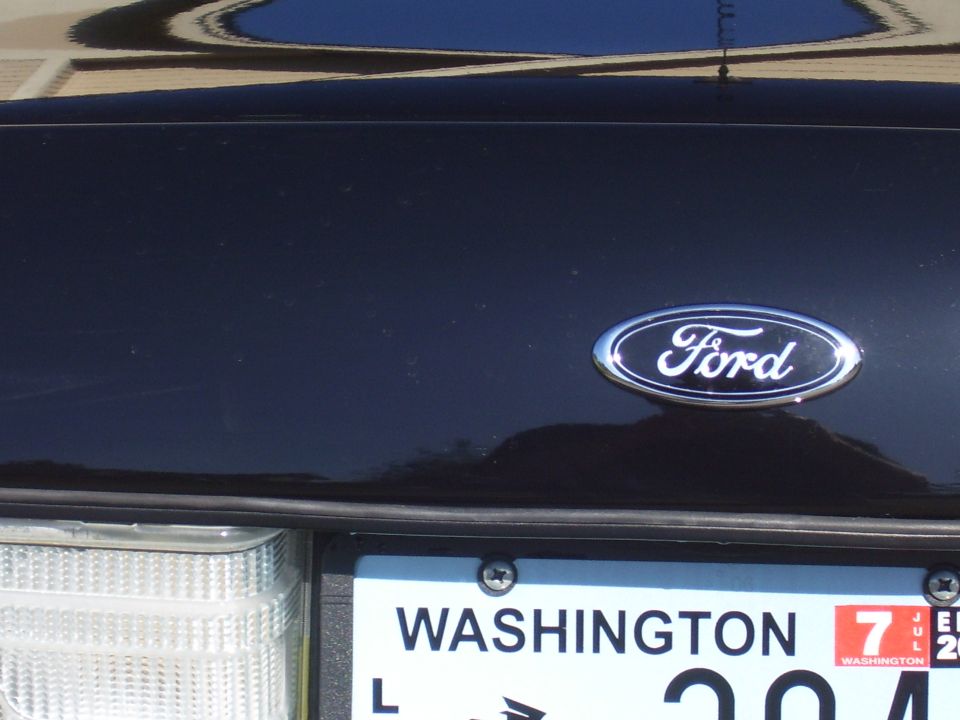 Close-up of chrome Ford oval emblem on a dark blue tailgate above a Washington license plate