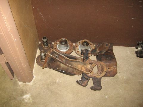 1974 Ford F-100 - Various rusty axle parts, likely for a truck, are laid out on the floor.