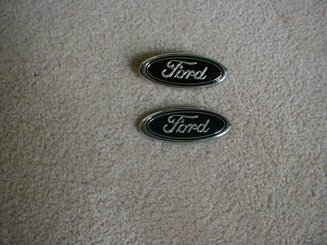Two Ford oval emblems on carpet