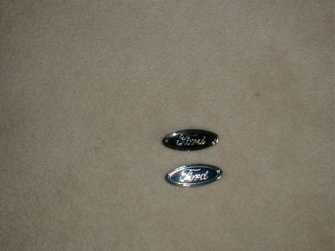 2002 Ford Crown Victoria - Two Ford oval emblems are shown against a textured background.