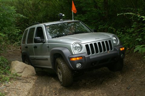 2006 Jeep Liberty - A silver 2006 Jeep Liberty navigates a rocky off-road trail surrounded by dense foliage.
