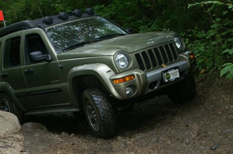 2006 Jeep Liberty - A green 2006 Jeep Liberty navigates a rocky, wooded trail.