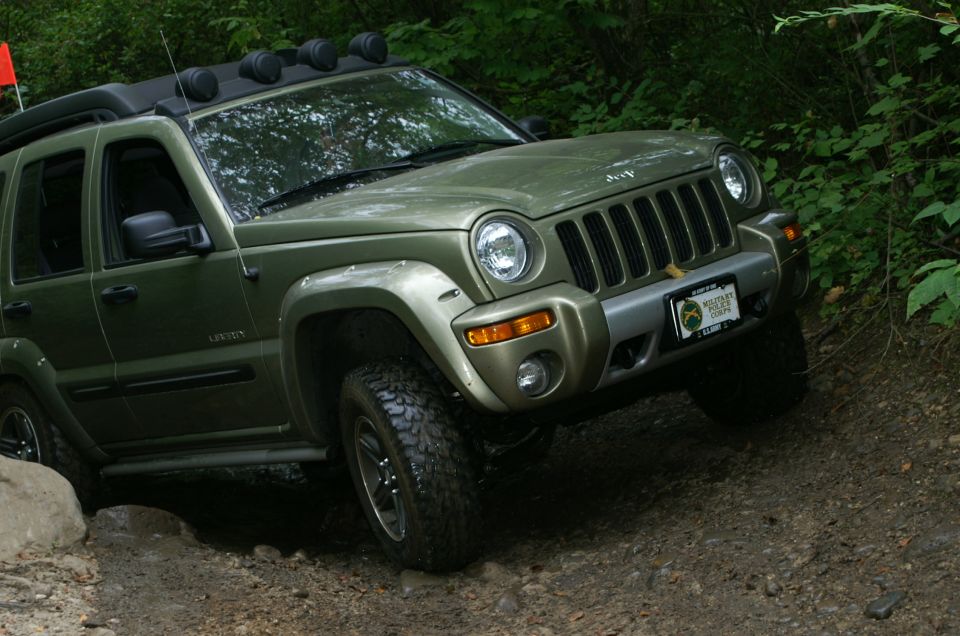 Green 2006 Jeep Liberty on a dirt trail, front 3/4 view