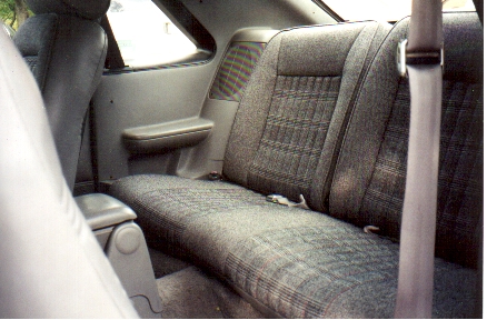 1989 Ford Mustang - Rear interior view of a 1989 Ford Mustang GT, showing the patterned fabric seats and door panel.