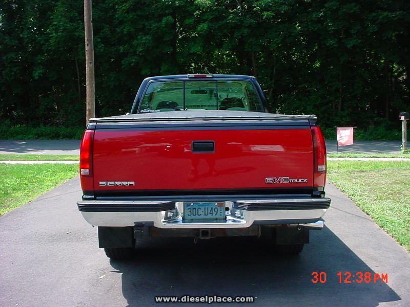 Rear of red-and-black two-tone GMC Sierra pickup with CT plate, parked on a driveway