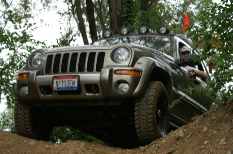 2006 Jeep Liberty - A Jeep Liberty navigates an off-road trail, its tires gripping the dirt as it climbs.