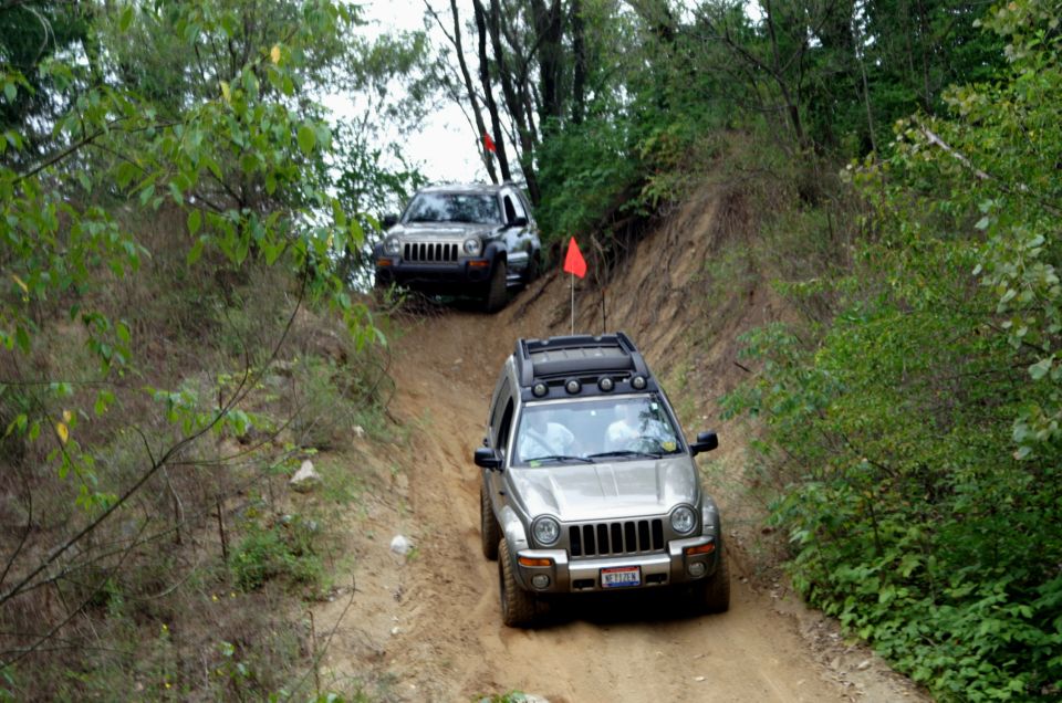Silver 2006 Jeep Liberty driving down a dirt trail, with another Jeep behind it