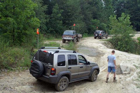 2006 Jeep Liberty - A silver 2006 Jeep Liberty navigates a muddy off-road trail, with other SUVs following behind.