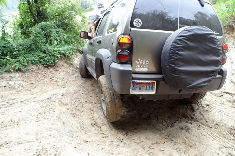2006 Jeep Liberty - Rear view of a 2006 Jeep Liberty navigating a muddy, off-road trail with another vehicle ahead.