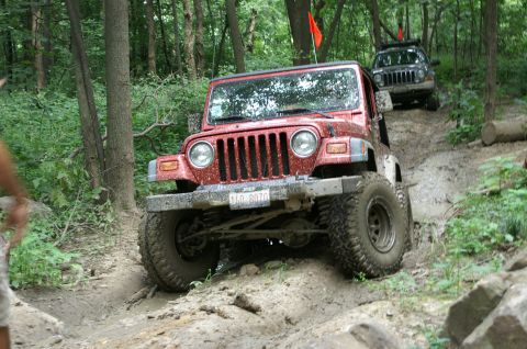 2006 Jeep Liberty - Two Jeeps navigate a challenging off-road trail through a wooded area.