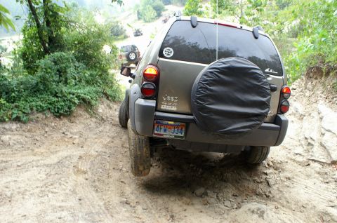 2006 Jeep Liberty - A 2006 Jeep Liberty navigates a challenging off-road trail with other vehicles in the background.