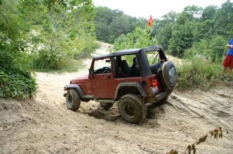 2006 Jeep Liberty - A red Jeep Wrangler tackles a rocky, off-road trail on a sunny day.