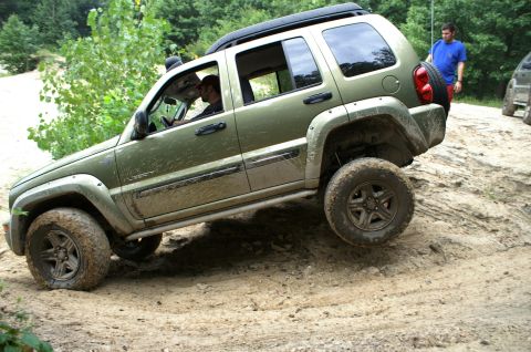 2006 Jeep Liberty - A green 2006 Jeep Liberty navigates a challenging off-road terrain, with another vehicle visible in the background.