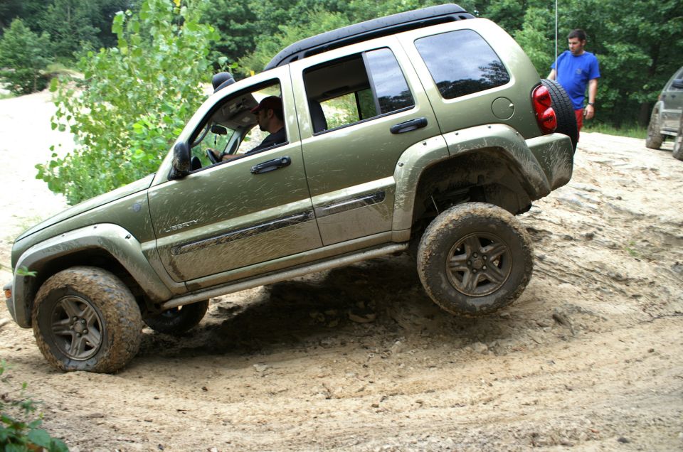 Green 2006 Jeep Liberty climbing a dirt hill off-road