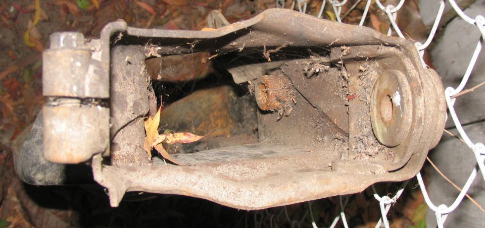 rusted metal suspension component with bolts and cobwebs