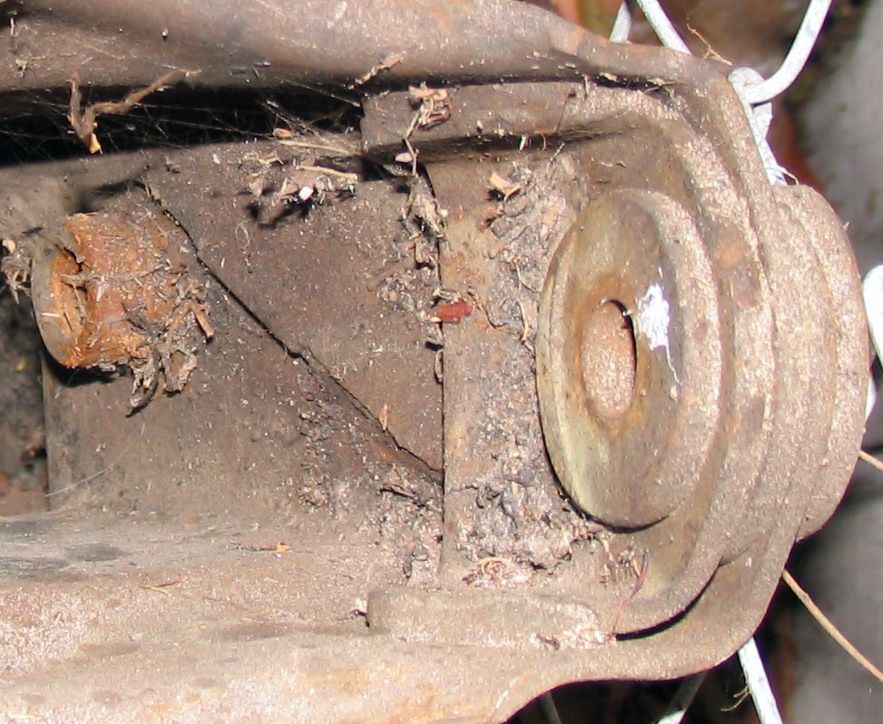Rusted metal suspension component with dirt and cobwebs