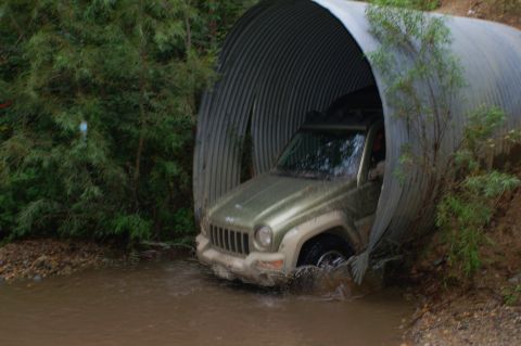 2006 Jeep Liberty - A Jeep Liberty navigates through a water-filled culvert, kicking up spray.