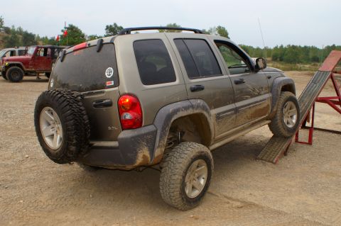 2006 Jeep Liberty - A muddy 2006 Jeep Liberty navigates an off-road obstacle course with another Jeep in the background.