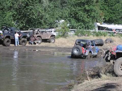 1979 Ford Bronco - Off-road vehicles navigate a muddy terrain during an event.