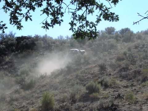 1979 Ford Bronco - A vehicle navigates a dry, brush-covered hillside, creating a cloud of dust.