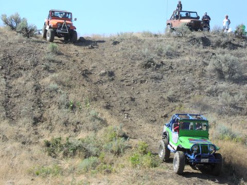 1979 Ford Bronco - Off-road vehicles navigate a steep, arid slope during an outdoor event.