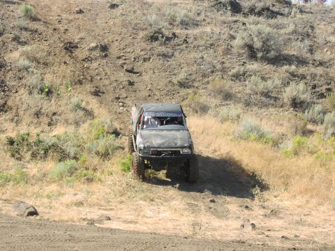 1979 Ford Bronco - Off-road Toyota pickup truck navigates a steep, dry hillside during an event.