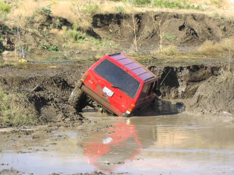 1979 Ford Bronco - This red Jeep Cherokee is stuck in a muddy ditch after going off-road.