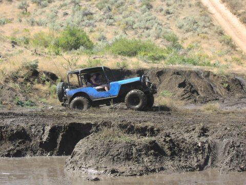 1979 Ford Bronco - Off-road jeep navigates a muddy terrain during an outdoor event.