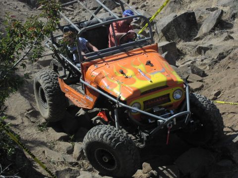 1979 Ford Bronco - This heavily modified off-road vehicle navigates a challenging rocky course, its custom roll cage and large tires built for extreme terrain.