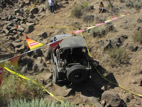 1979 Ford Bronco - Off-road vehicle climbs a steep, rocky incline during an event marked by caution tape.