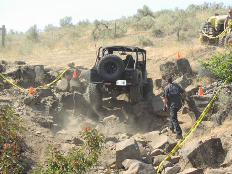1979 Ford Bronco - A Jeep Wrangler tackles a challenging rocky terrain during an off-road event, with another vehicle visible in the background.