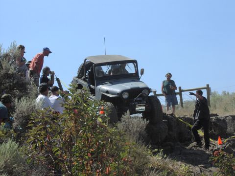 1979 Ford Bronco - An off-road vehicle navigates a rocky incline with spectators watching.
