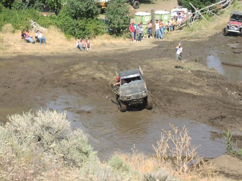 1979 Ford Bronco - An off-road vehicle navigates a challenging mud course while onlookers observe the event.