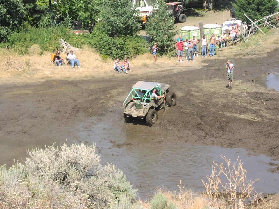 Off-road buggy with roll cage navigating a muddy track