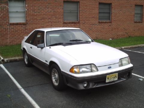 1989 Ford Mustang - This 1989 Ford Mustang coupe is parked in a lot with a brick building in the background.