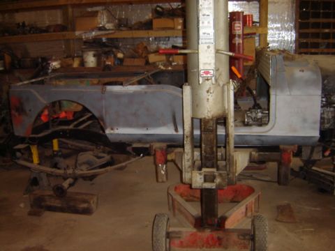 1992 Ford Bronco - This Jeep CJ-5 body is undergoing restoration work, supported by a lift in a cluttered workshop.